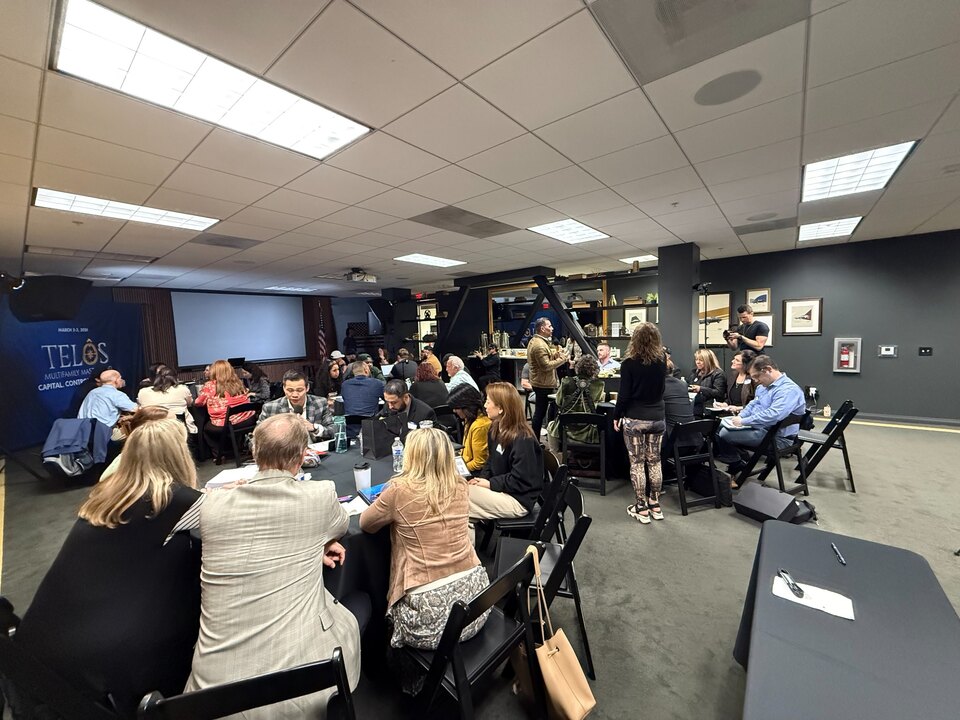 Attendees gathered around tables for a March 2026 TELŌS discussion